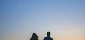 man and woman holding hands in silhouette photography